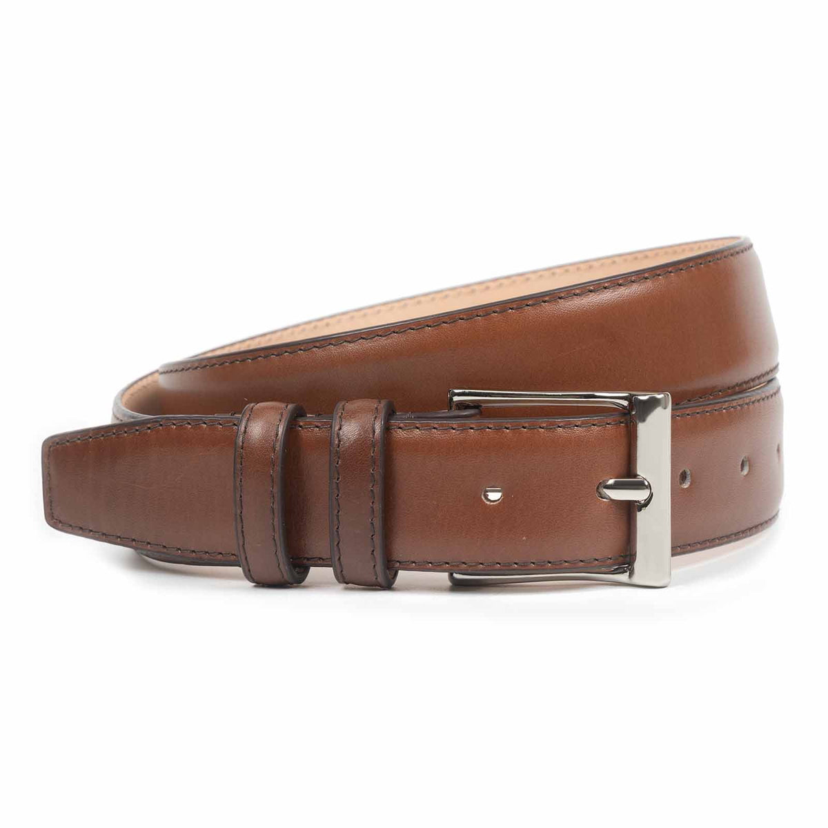 Meermin cognac leather belt, coiled to show buckle and keeper loops, with polished nickel-finish buckle in close focus