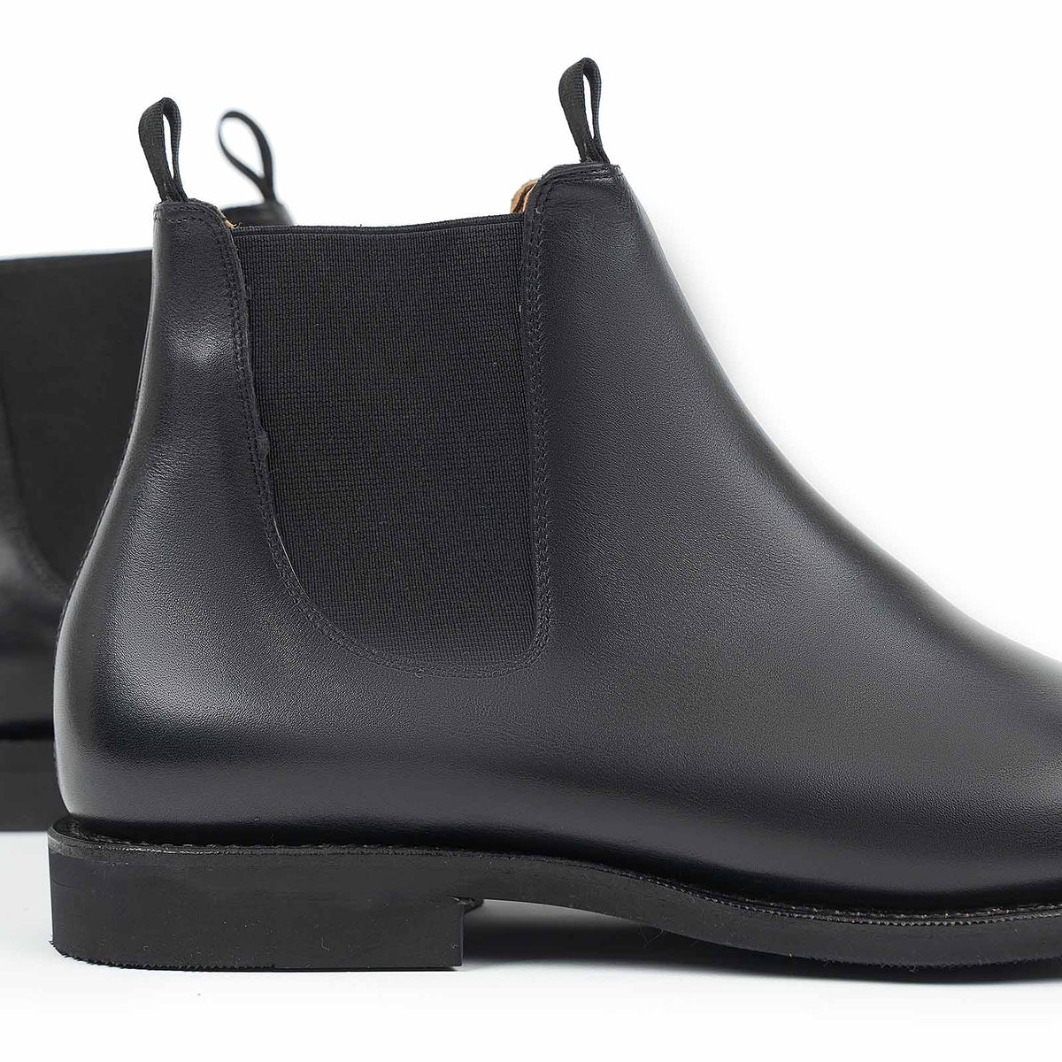 Meermin black silkcalf Chelsea boot, close-up rear/heel view showing elastic side panel, pull tabs, and diamond latex rubber sole