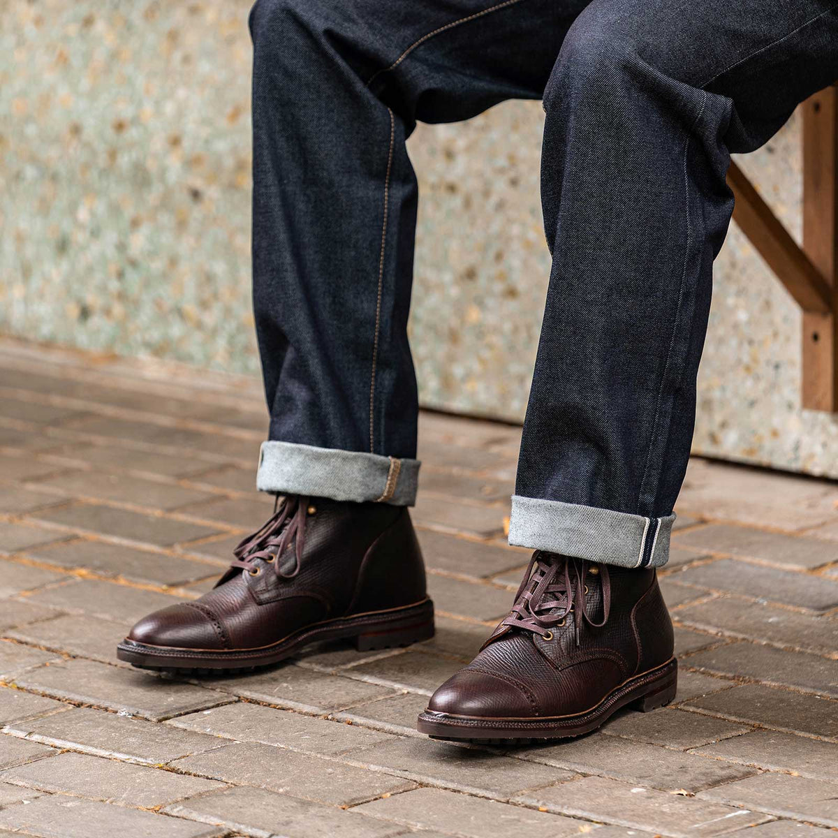 Meermin Polo oiled crossboard cap-toe boots worn with cuffed selvedge denim, seated pose showing textured leather and lug soles